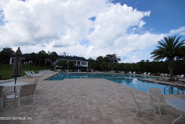 community pool with a patio area and fence