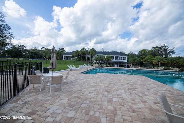 pool with a lawn, a patio area, and fence