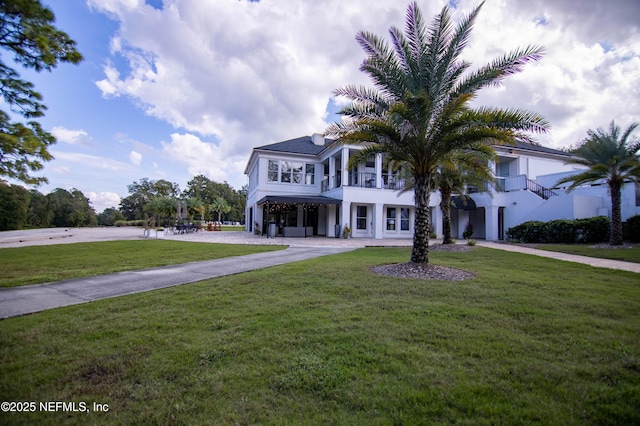 view of front of home featuring a balcony, concrete driveway, and a front yard