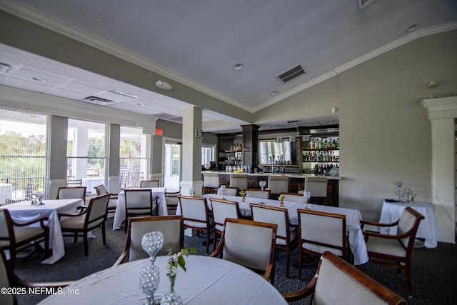 dining area featuring lofted ceiling, visible vents, crown molding, and ornate columns