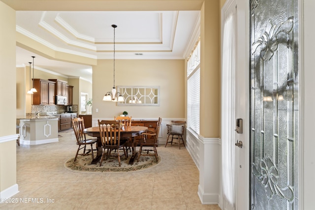 dining area with a raised ceiling, crown molding, an inviting chandelier, and light tile patterned floors