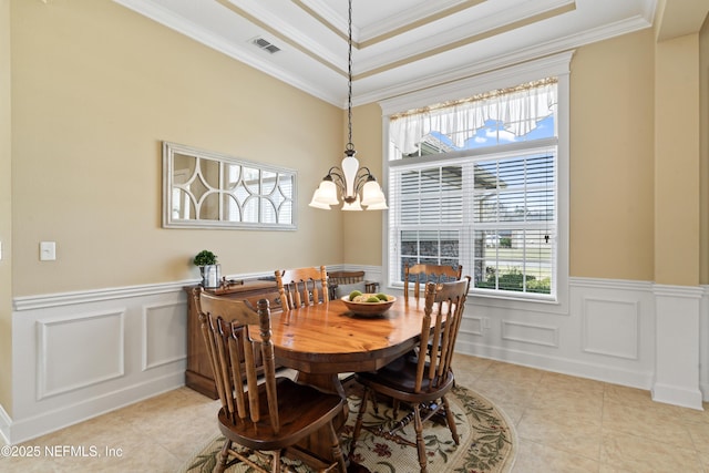 dining space with a wainscoted wall, visible vents, crown molding, and an inviting chandelier