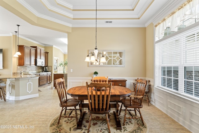 dining room featuring a wainscoted wall, a tray ceiling, visible vents, and a healthy amount of sunlight