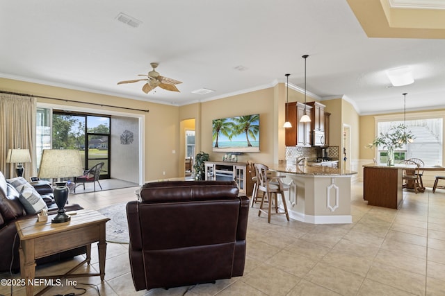 living room featuring light tile patterned floors, a ceiling fan, a wealth of natural light, and crown molding