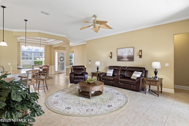 living area with visible vents, ornamental molding, a ceiling fan, light tile patterned flooring, and baseboards