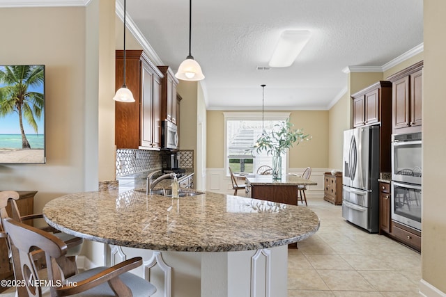 kitchen with a center island, crown molding, appliances with stainless steel finishes, a sink, and a peninsula