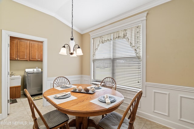 dining room with light tile patterned floors, lofted ceiling, a chandelier, a wainscoted wall, and washer / dryer