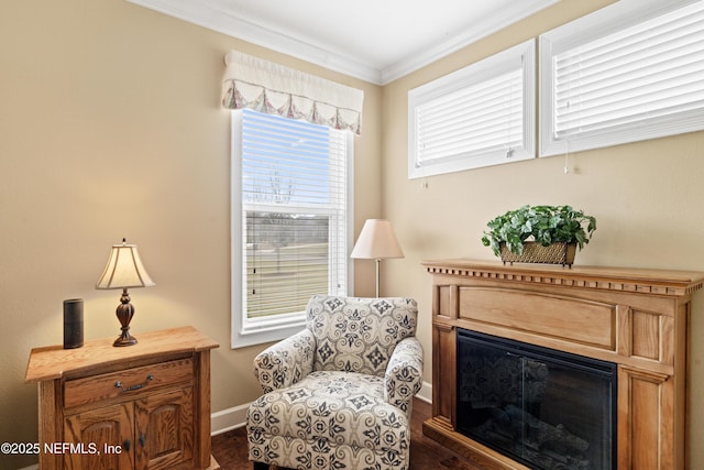 living area featuring dark wood-style floors, ornamental molding, a glass covered fireplace, and baseboards