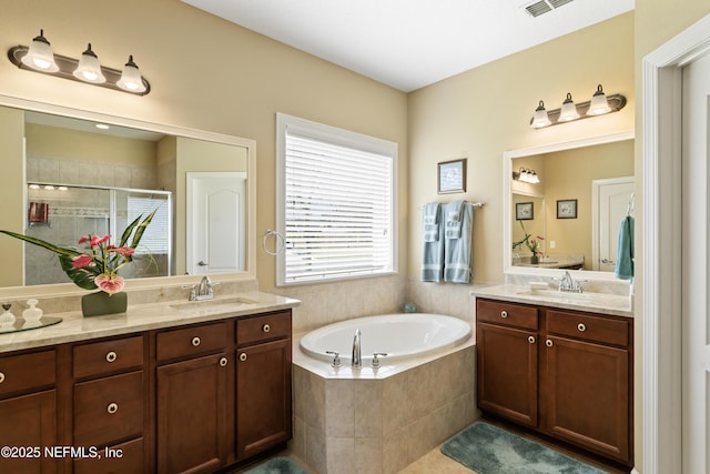 bathroom featuring visible vents, a stall shower, a garden tub, and vanity