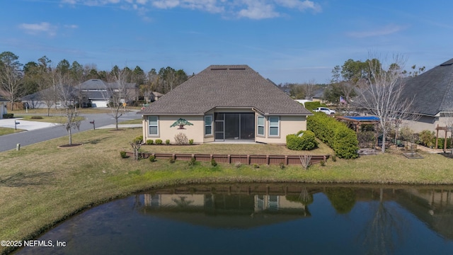 rear view of property with a water view and a lawn