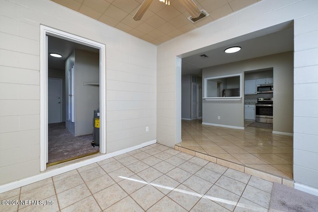 spare room with ceiling fan and light tile patterned floors