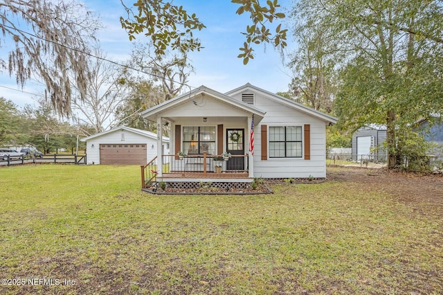 bungalow-style home featuring a porch, a garage, a front lawn, and an outdoor structure