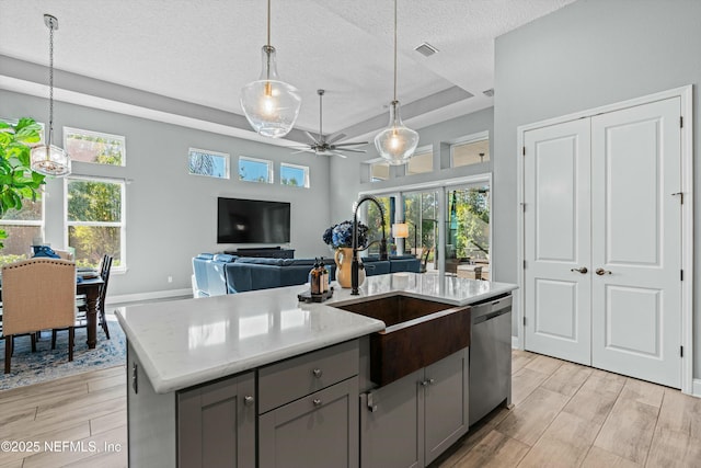 kitchen with stainless steel dishwasher, pendant lighting, a center island with sink, ceiling fan, and sink