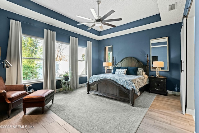 bedroom with a raised ceiling, a textured ceiling, and ceiling fan