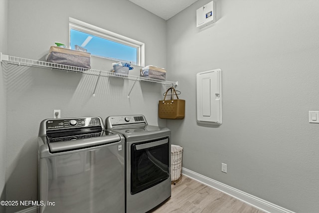 clothes washing area featuring light wood-type flooring and washer and clothes dryer