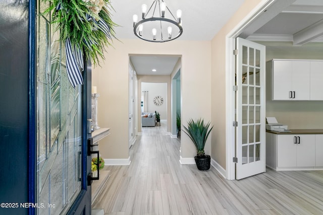 hallway featuring light hardwood / wood-style floors, beamed ceiling, french doors, and a chandelier