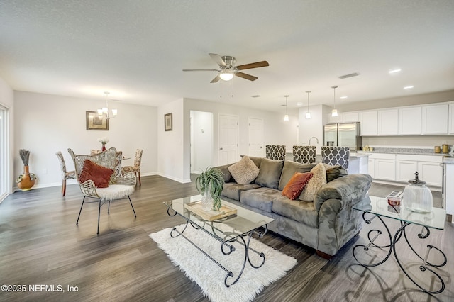 living room featuring ceiling fan with notable chandelier and dark hardwood / wood-style flooring