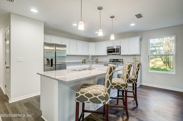 kitchen with white cabinetry, sink, stainless steel appliances, pendant lighting, and a breakfast bar area