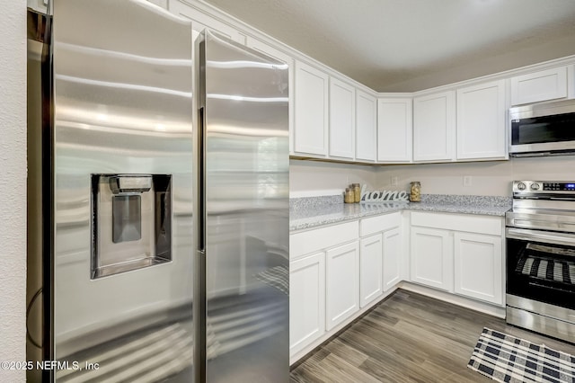 kitchen with white cabinets, light stone countertops, hardwood / wood-style floors, and appliances with stainless steel finishes