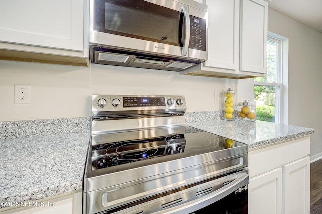 kitchen featuring hardwood / wood-style floors, stainless steel appliances, white cabinetry, and light stone counters