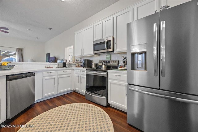 kitchen with a textured ceiling, appliances with stainless steel finishes, white cabinetry, dark hardwood / wood-style flooring, and backsplash