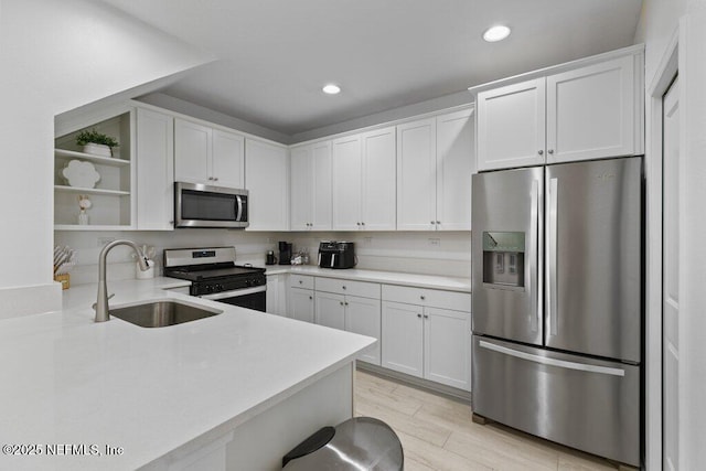 kitchen with kitchen peninsula, white cabinetry, sink, and appliances with stainless steel finishes