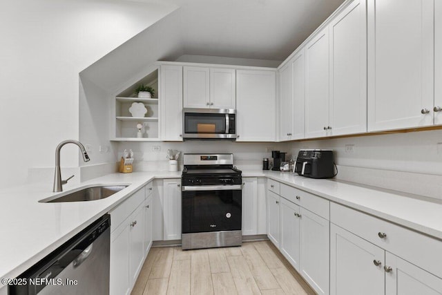 kitchen with white cabinets, stainless steel appliances, light hardwood / wood-style floors, and sink