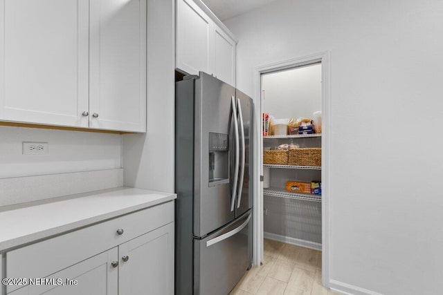 kitchen with white cabinets, light hardwood / wood-style floors, and stainless steel fridge with ice dispenser