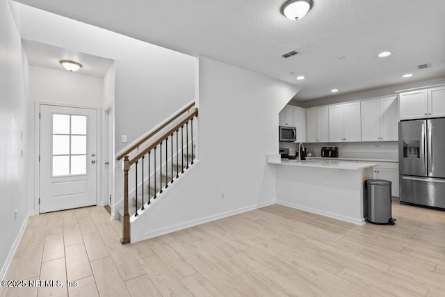 kitchen with sink, kitchen peninsula, a breakfast bar area, white cabinets, and appliances with stainless steel finishes