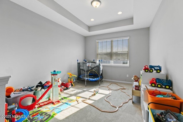 rec room featuring a raised ceiling and light carpet