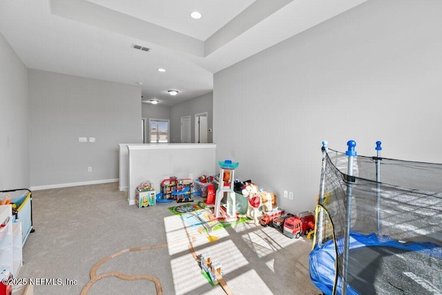 playroom with a raised ceiling and carpet floors