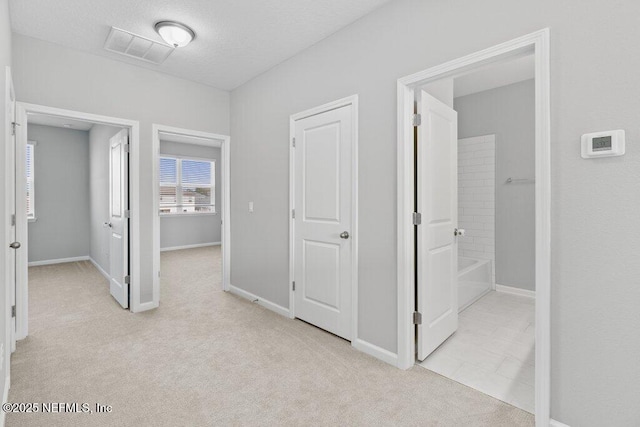 corridor featuring a textured ceiling and light carpet