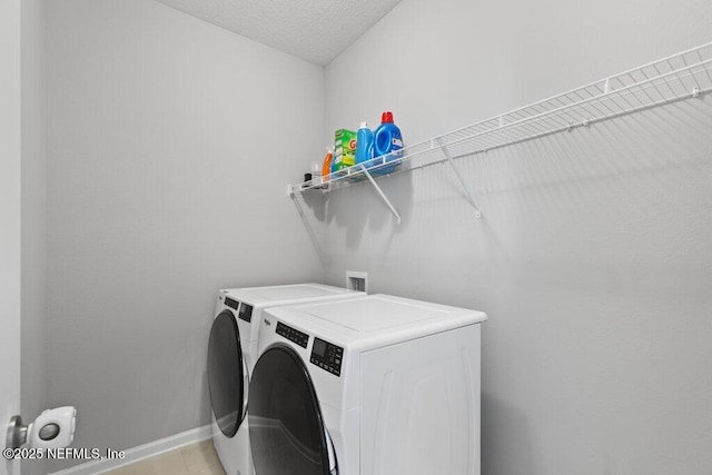 laundry area featuring a textured ceiling and washing machine and dryer