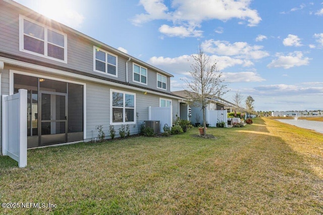 rear view of property featuring central air condition unit, a sunroom, and a yard