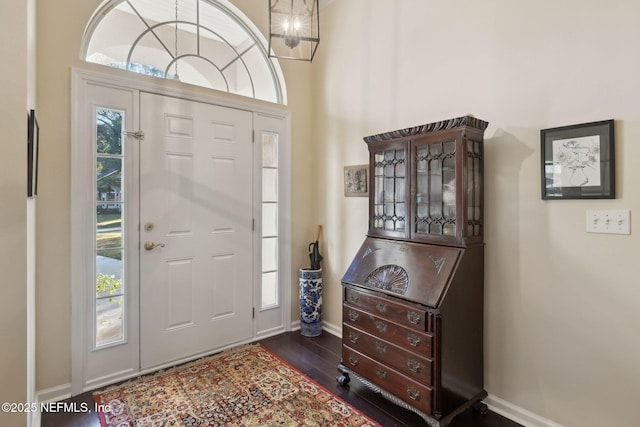 foyer featuring a healthy amount of sunlight, dark hardwood / wood-style floors, and an inviting chandelier