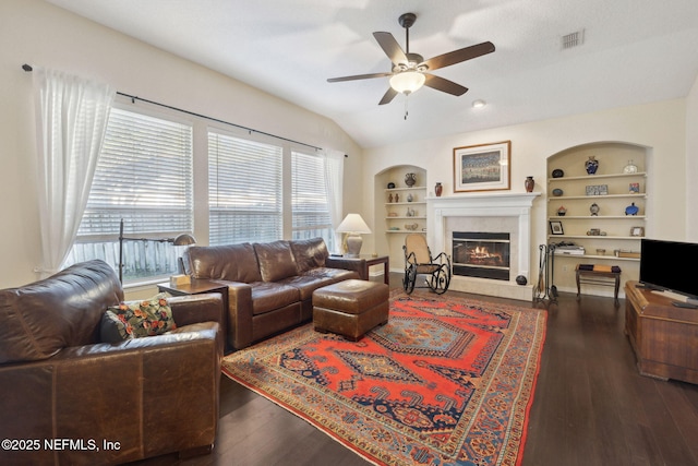 living room with ceiling fan, built in features, dark hardwood / wood-style floors, and lofted ceiling