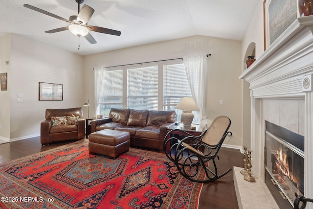 living room with hardwood / wood-style flooring, ceiling fan, a tile fireplace, and vaulted ceiling