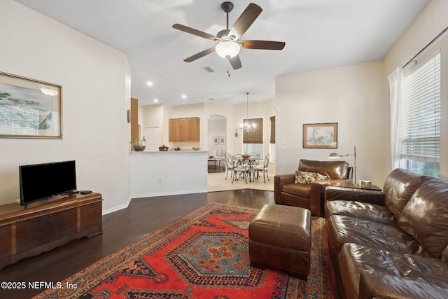 living room with ceiling fan with notable chandelier and dark hardwood / wood-style floors