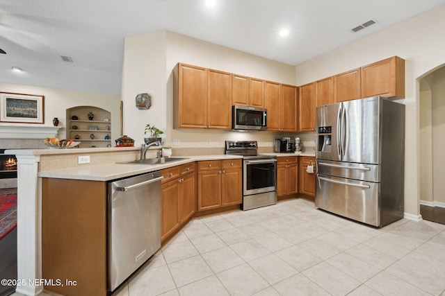 kitchen featuring kitchen peninsula, stainless steel appliances, sink, built in features, and light tile patterned flooring