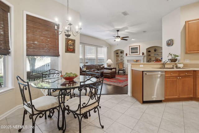 kitchen featuring built in shelves, sink, stainless steel dishwasher, decorative light fixtures, and ceiling fan with notable chandelier