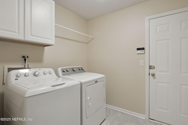 clothes washing area with cabinets, washer and dryer, and a textured ceiling