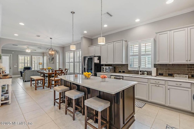 kitchen with appliances with stainless steel finishes, ceiling fan with notable chandelier, sink, a center island, and hanging light fixtures