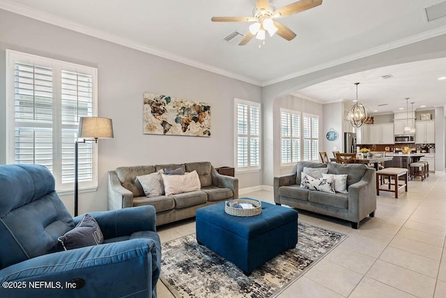 tiled living room with ceiling fan with notable chandelier, crown molding, and a healthy amount of sunlight