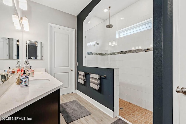 bathroom featuring a tile shower, hardwood / wood-style floors, and vanity