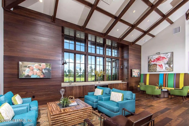 interior space with beamed ceiling, wood walls, hardwood / wood-style floors, and a high ceiling