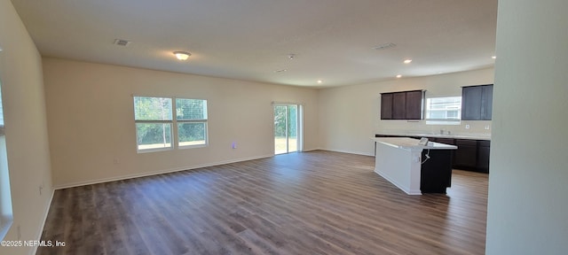 kitchen featuring dark brown cabinetry, dark hardwood / wood-style flooring, a center island, and sink