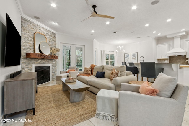 tiled living room with a stone fireplace, ceiling fan with notable chandelier, and ornamental molding