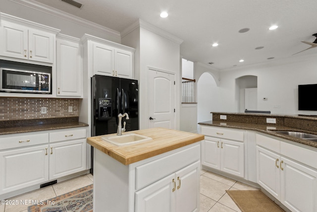 kitchen featuring white cabinets, black fridge, a kitchen island with sink, and sink