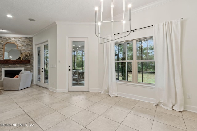 unfurnished dining area with french doors, crown molding, a chandelier, a stone fireplace, and light tile patterned flooring