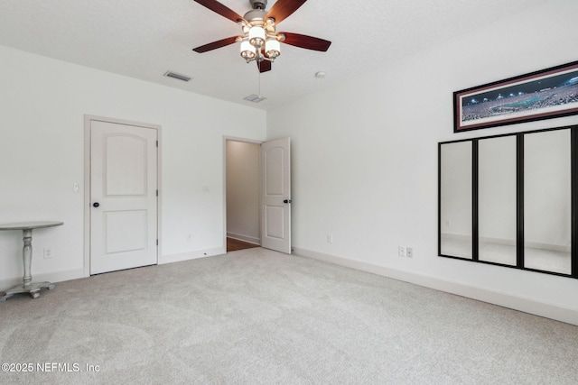 unfurnished bedroom featuring ceiling fan, light colored carpet, and a textured ceiling